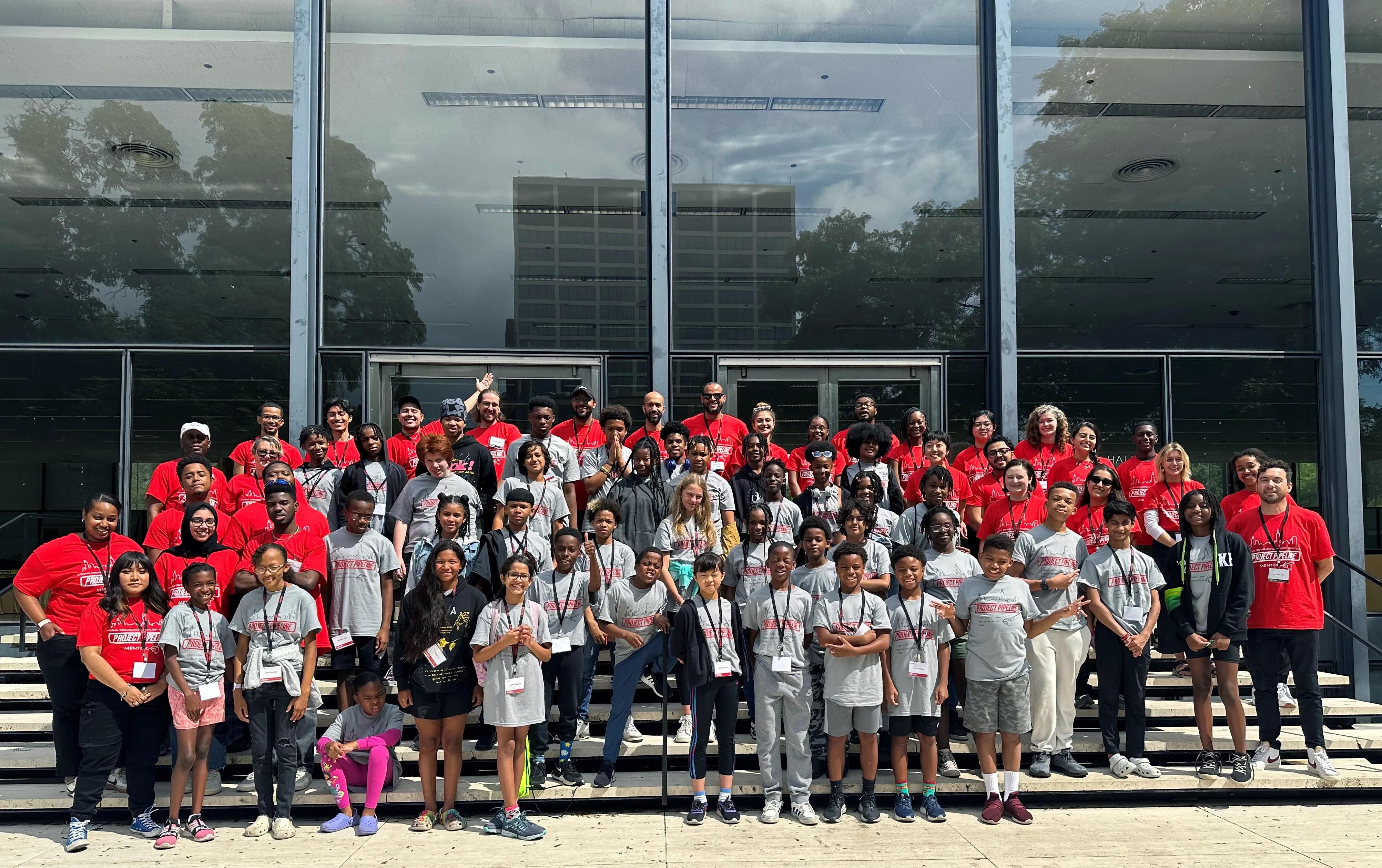 A group of students and mentors smile for a group photo at a Project Pipeline camp. 